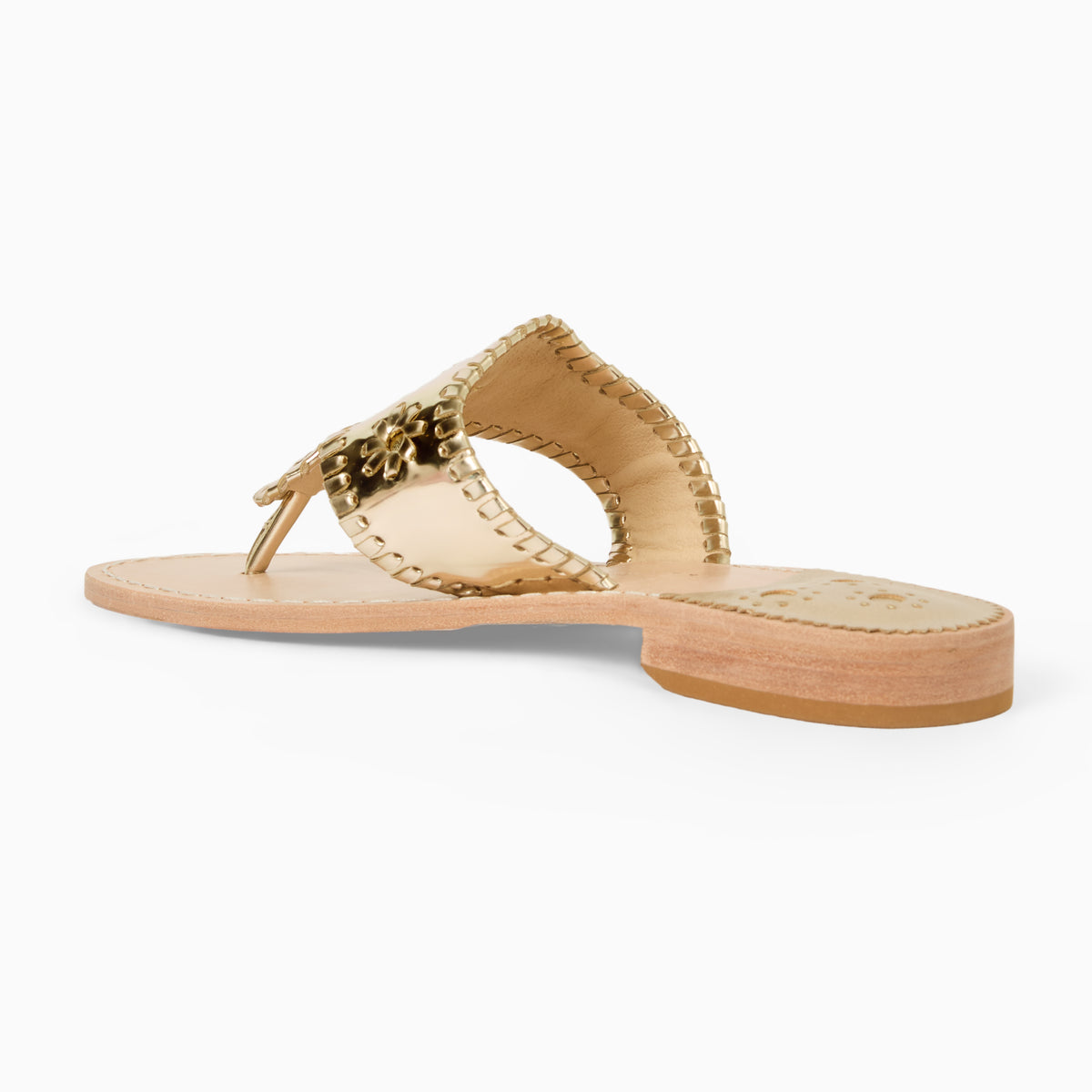 A single flat thong sandal shown in side profile on a clean white background. The sandal features metallic gold whipstitch strap with a decorative gold Rondell medallion, a light tan leather footbed, and a low stacked heel.